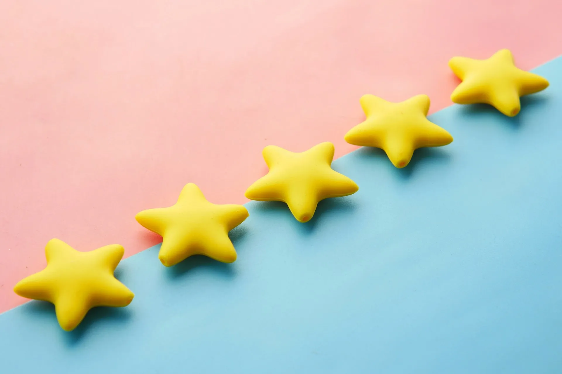 Five gold-star ratings lined up on a pink and blue background